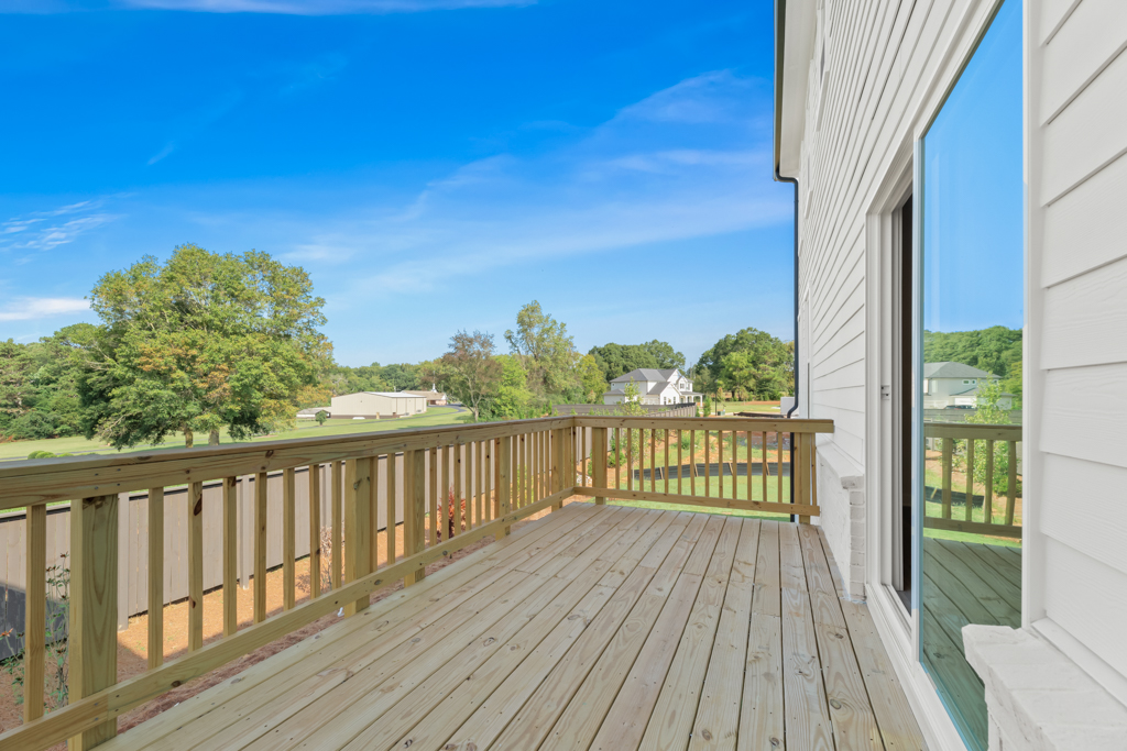 A wooden deck with a railing and trees in the background.