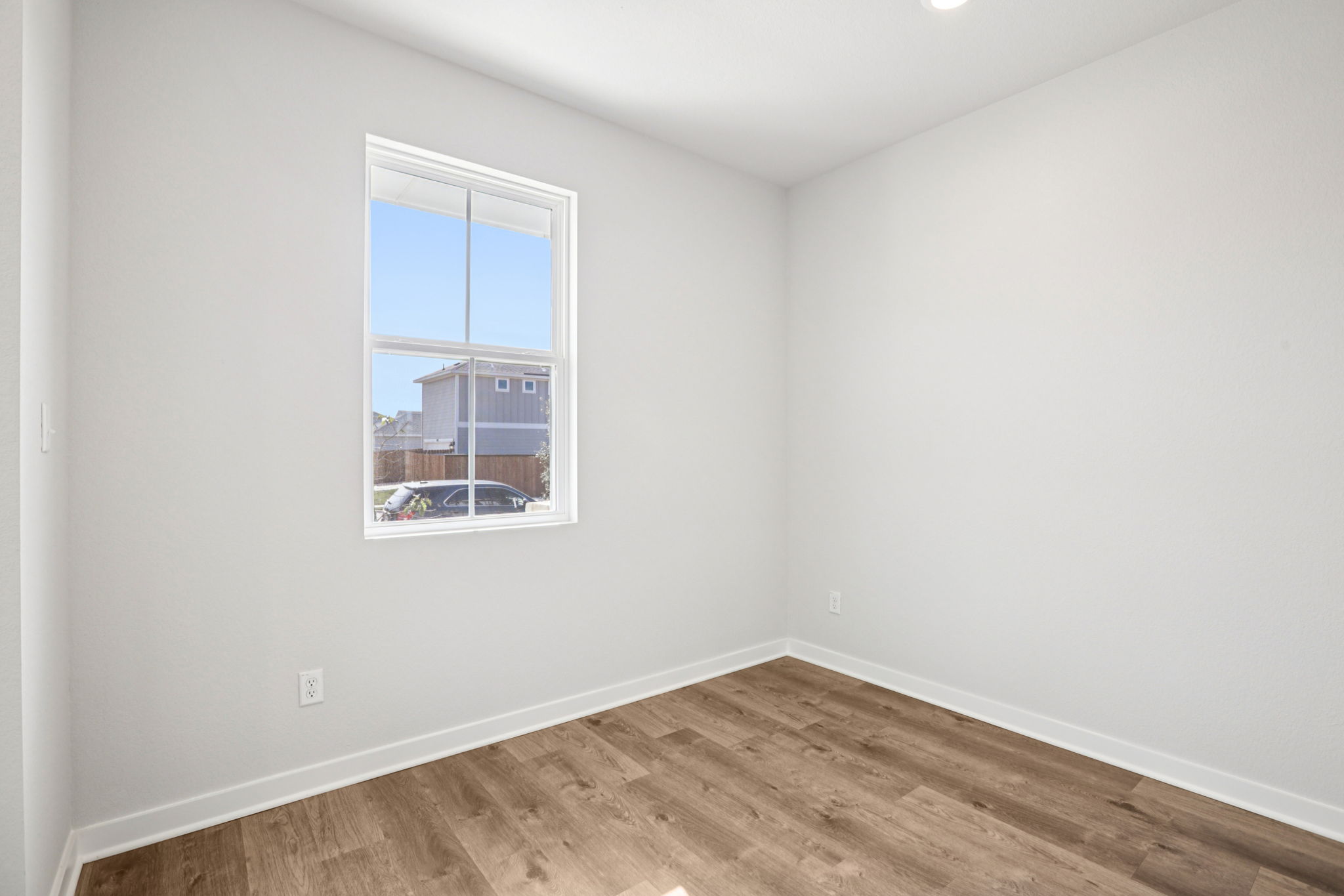 A room with a window and a wood floor.