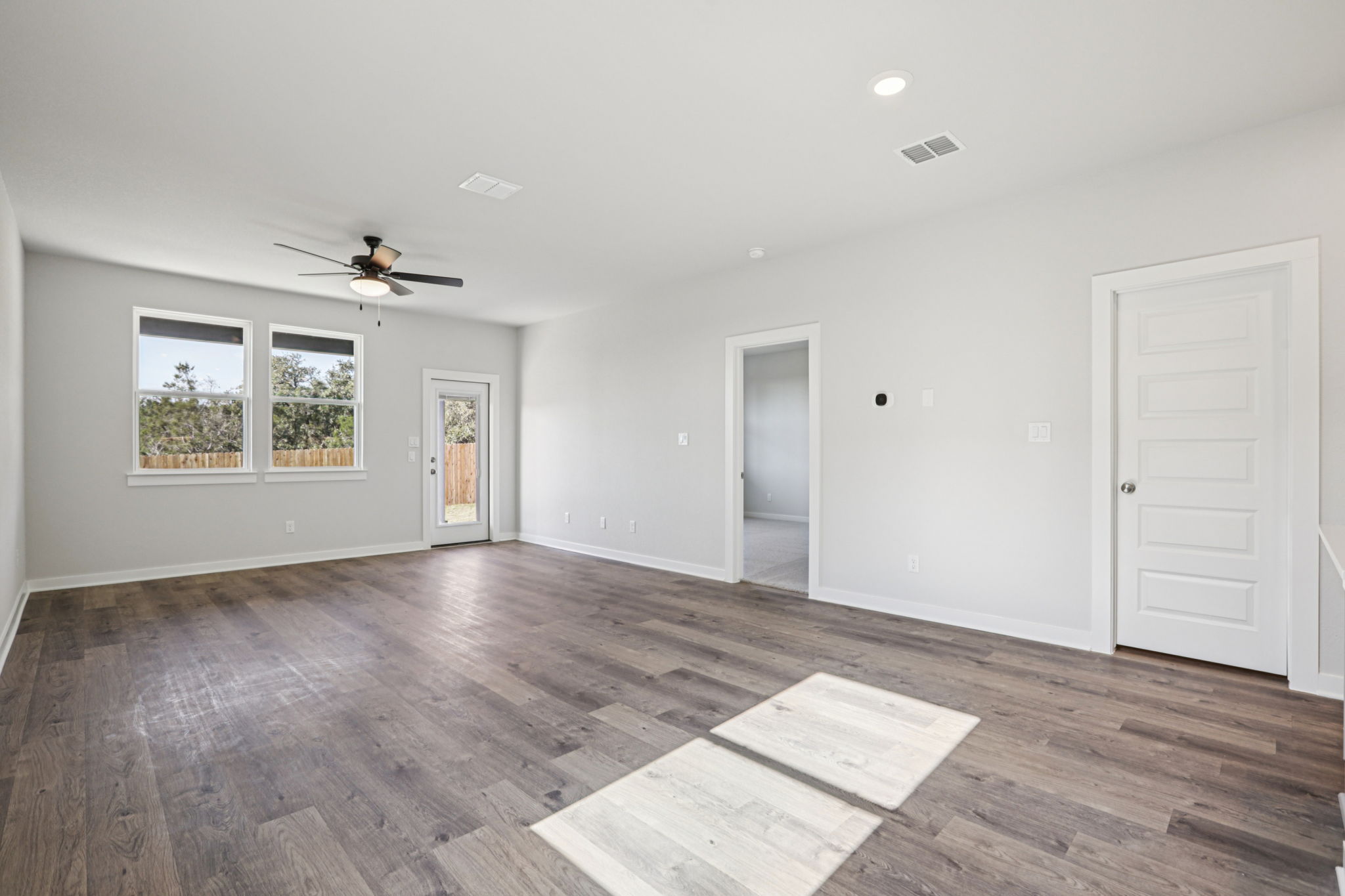 A room with a wood floor and a wood floor with a fan.