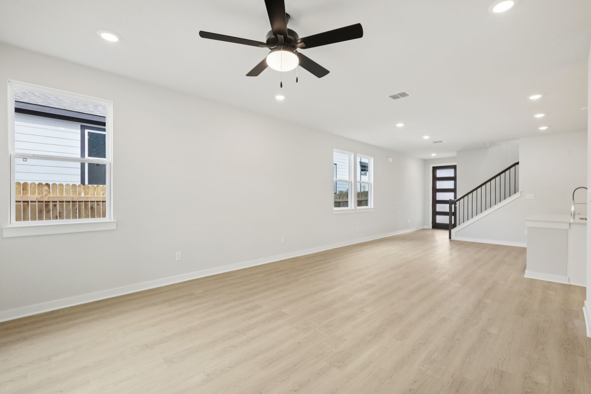 A room with a ceiling fan and a wood floor.