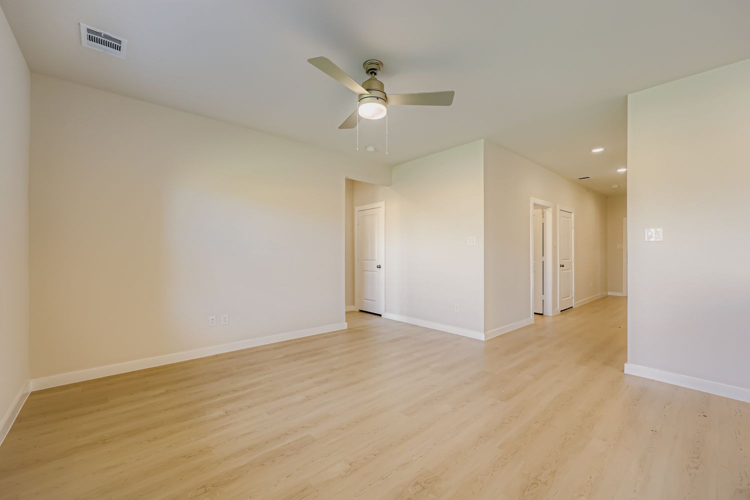 A room with a ceiling fan and wood floors.
