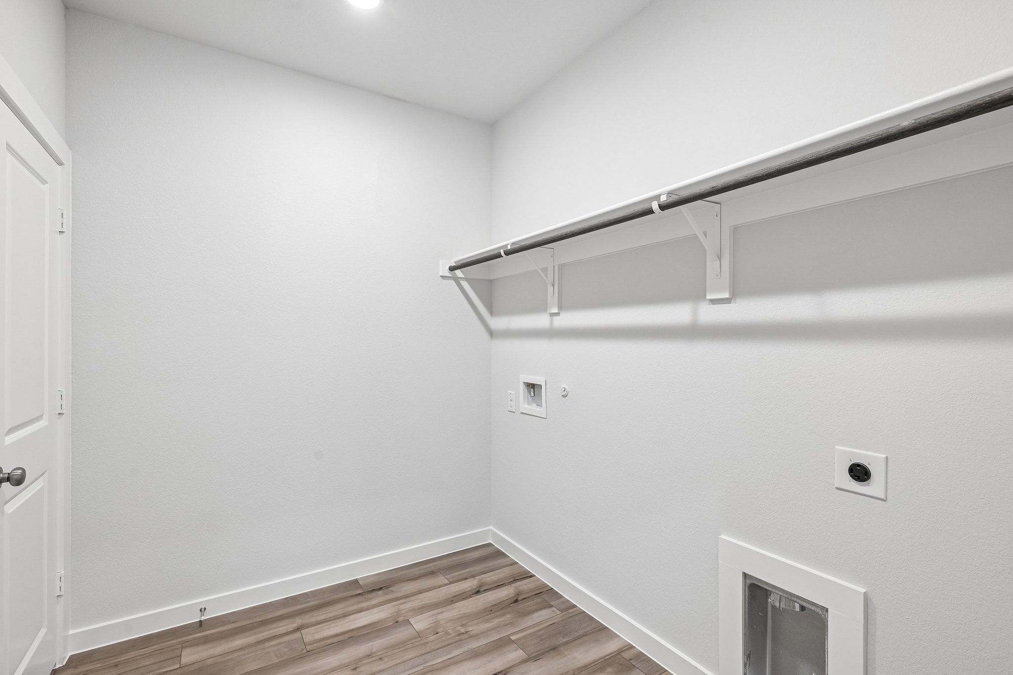 A white room with a wood floor and white walls.