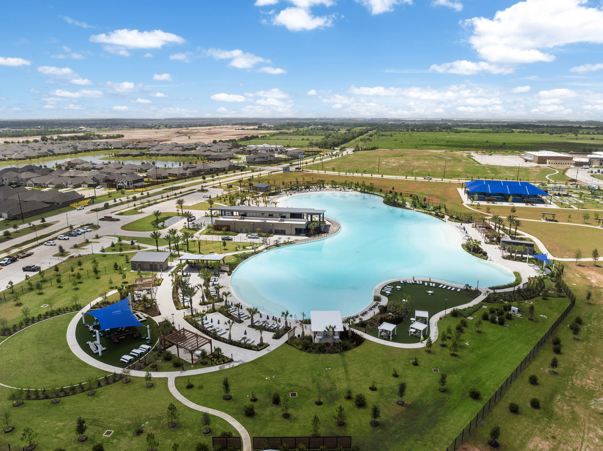 A large body of water surrounded by grass and buildings.