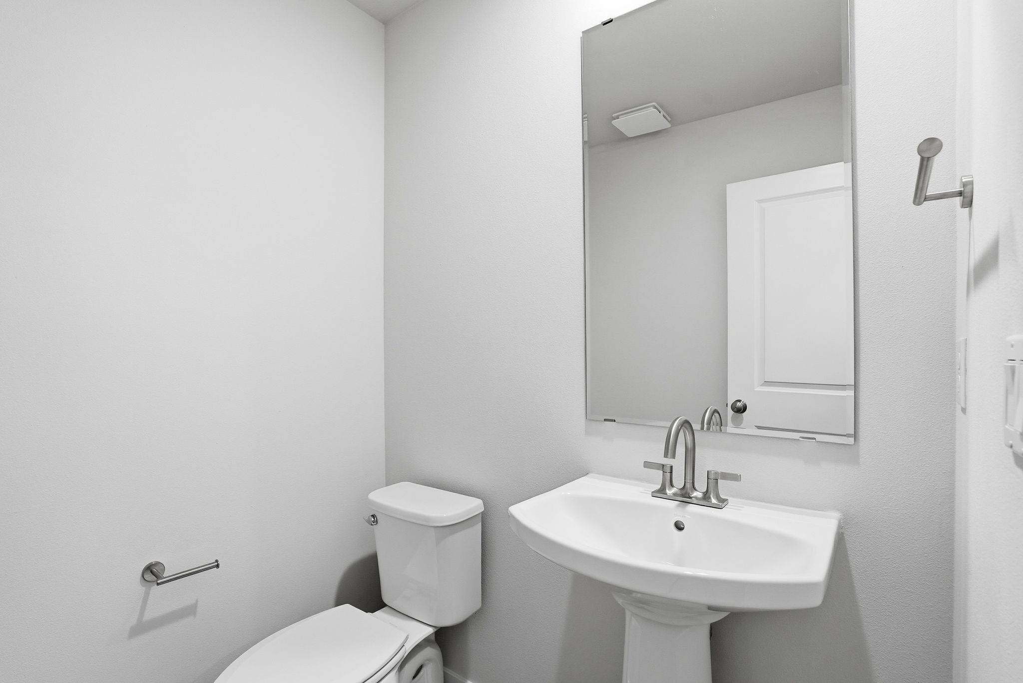 A bathroom with a sink toilet and mirror.