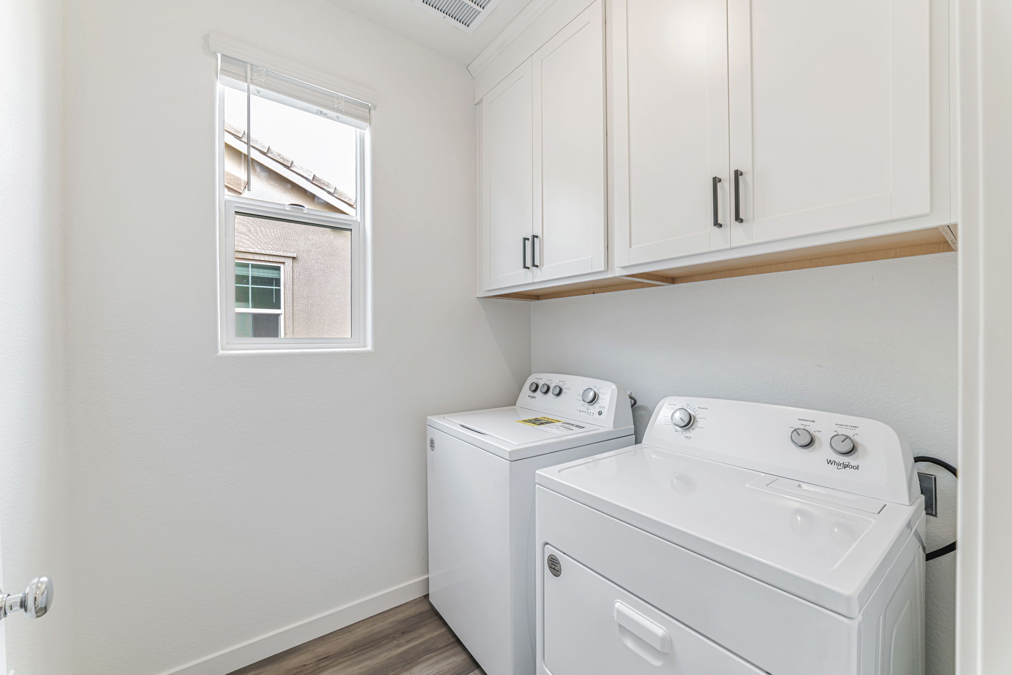A white laundry room with white cabinets.